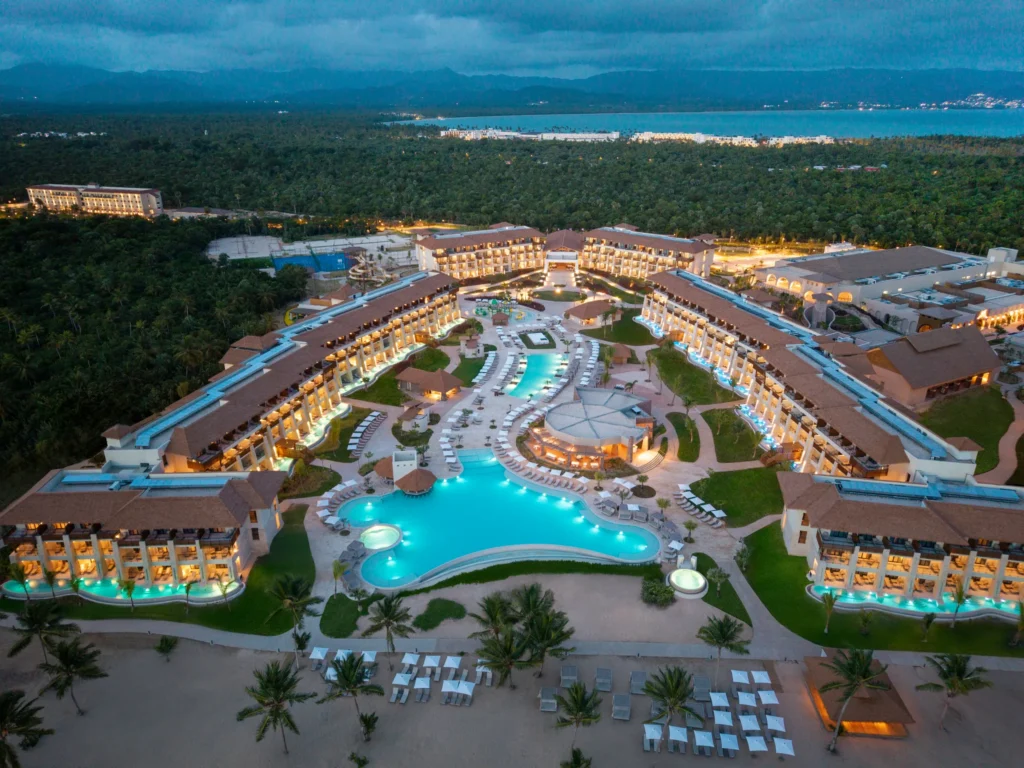 Sunrise aerial view of Dreams Playa Esmeralda Resort & Spa with illuminated pools and beachfront accommodations.