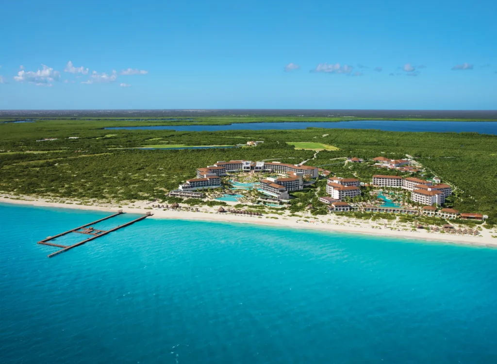 Aerial view of Dreams Playa Mujeres Resort with beachfront, pier, and dolphin habitat.