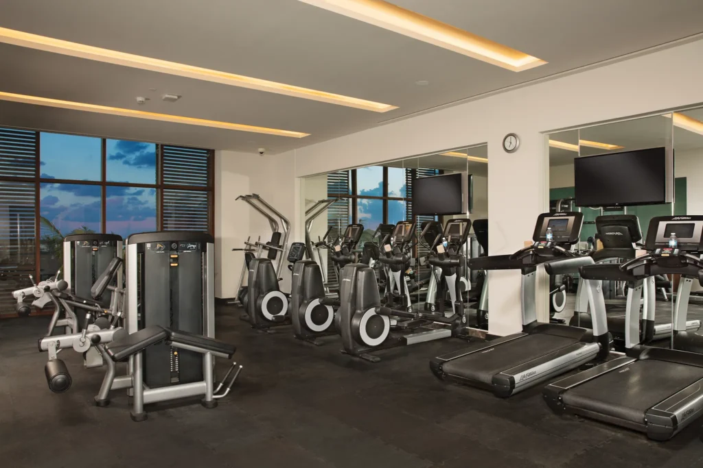 Modern fitness center with cardio machines and weights at Dreams Playa Mujeres Resort.