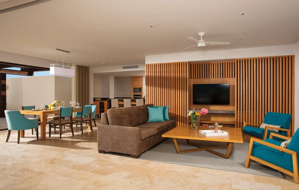 Open living room with sofa, TV, and dining area in large suite.