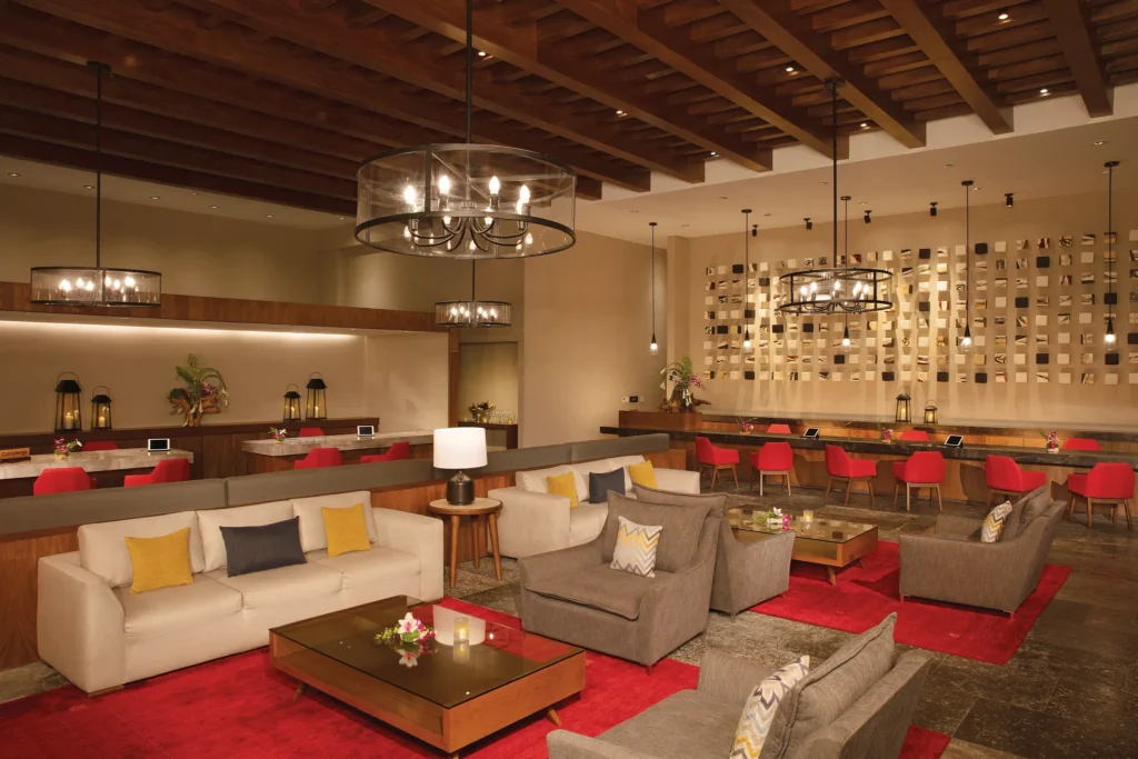 Stylish reception lounge with seating and concierge desks at Dreams Playa Mujeres Resort.