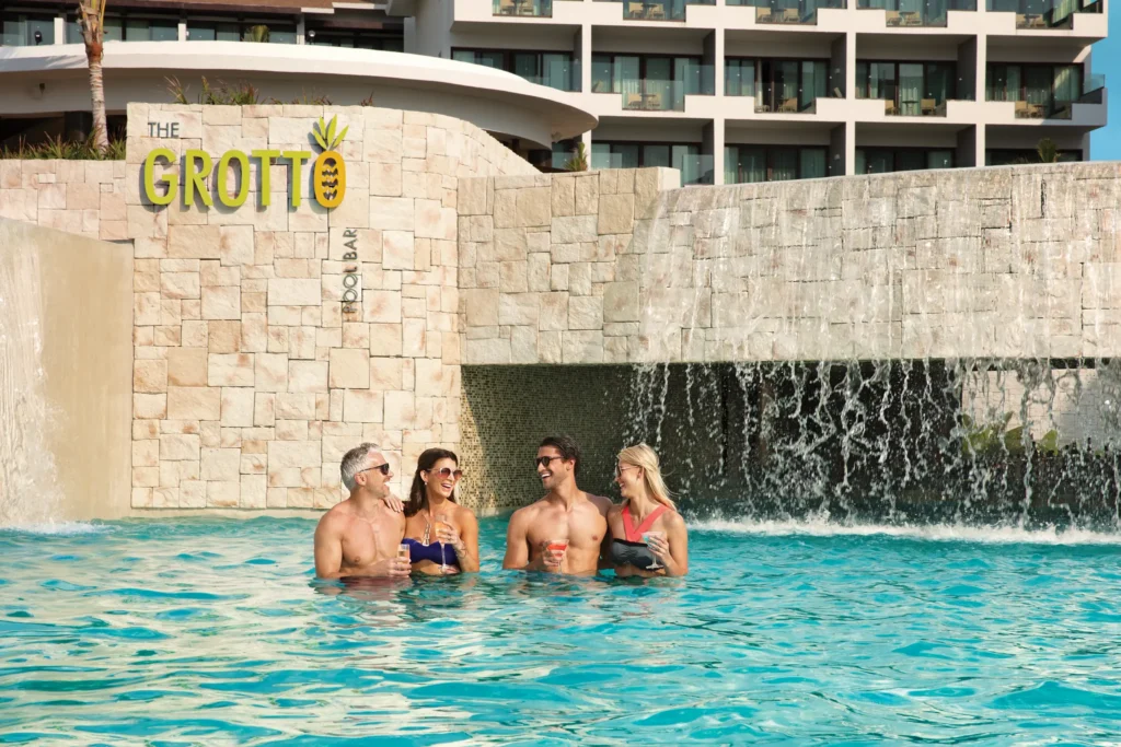 The Grotto poolside bar at Dreams Playa Mujeres Golf & Spa Resort featuring a shaded swim-up bar with refreshing cocktails and a relaxed tropical setting.