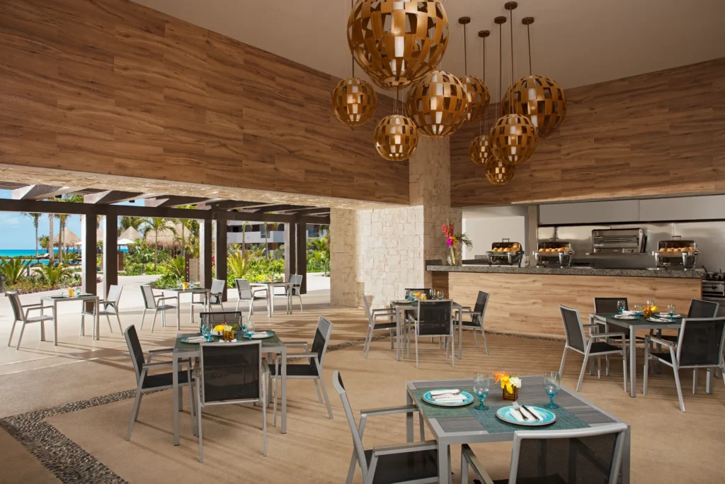 Tides poolside restaurant at Dreams Playa Mujeres Golf & Spa Resort featuring an open-air dining setting with ocean views and a relaxed tropical atmosphere.vv