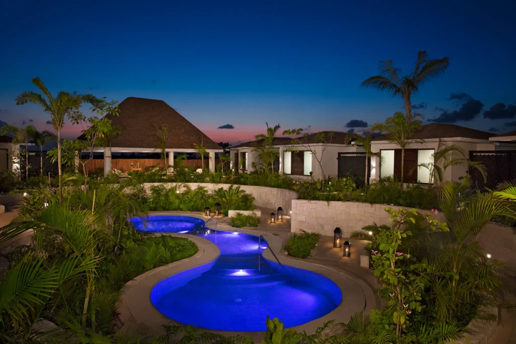 Illuminated hydrotherapy pool at night at Dreams Playa Mujeres Resort spa.