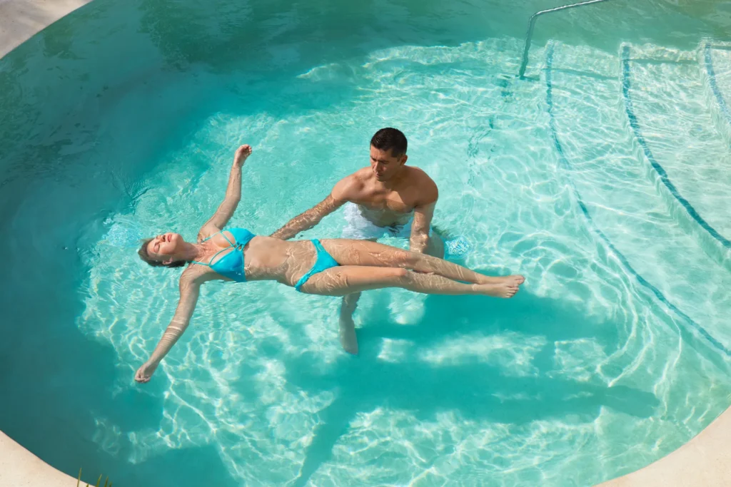 Guest receiving Watsu water therapy treatment in a pool at Dreams Playa Mujeres Resort spa.