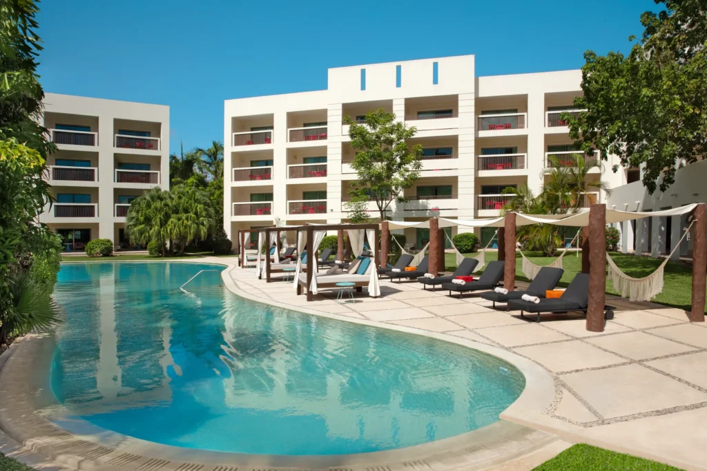 Tranquil adults-only pool with lounge chairs and cabanas at Dreams Puerto Morelos Resort & Spa.