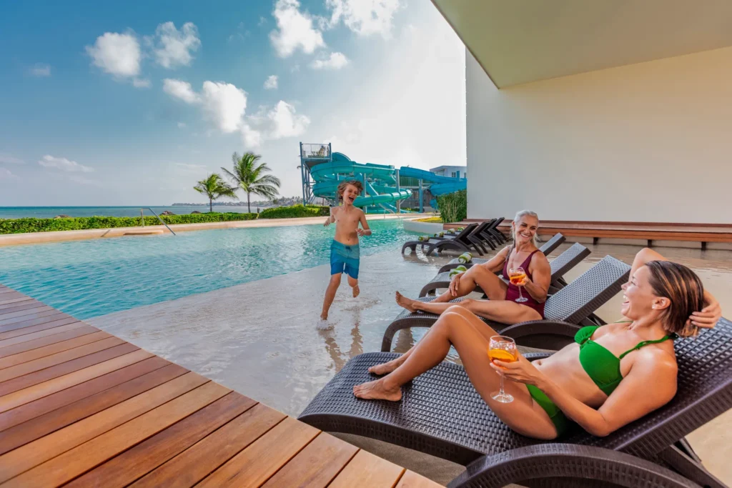 Family enjoying drinks in an infinity pool overlooking the ocean at Dreams Puerto Morelos Resort & Spa.