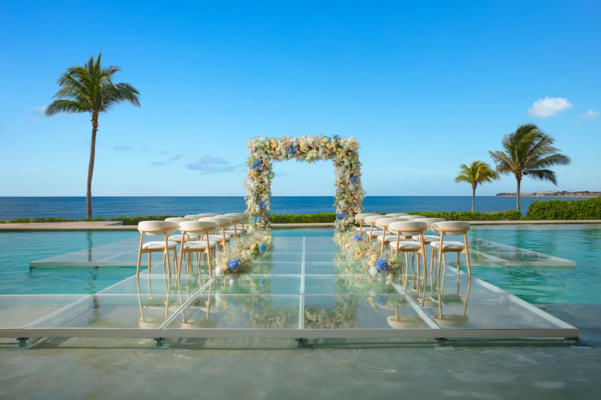 Infinity pool wedding ceremony setup with glass aisle at Dreams Puerto Morelos Resort & Spa