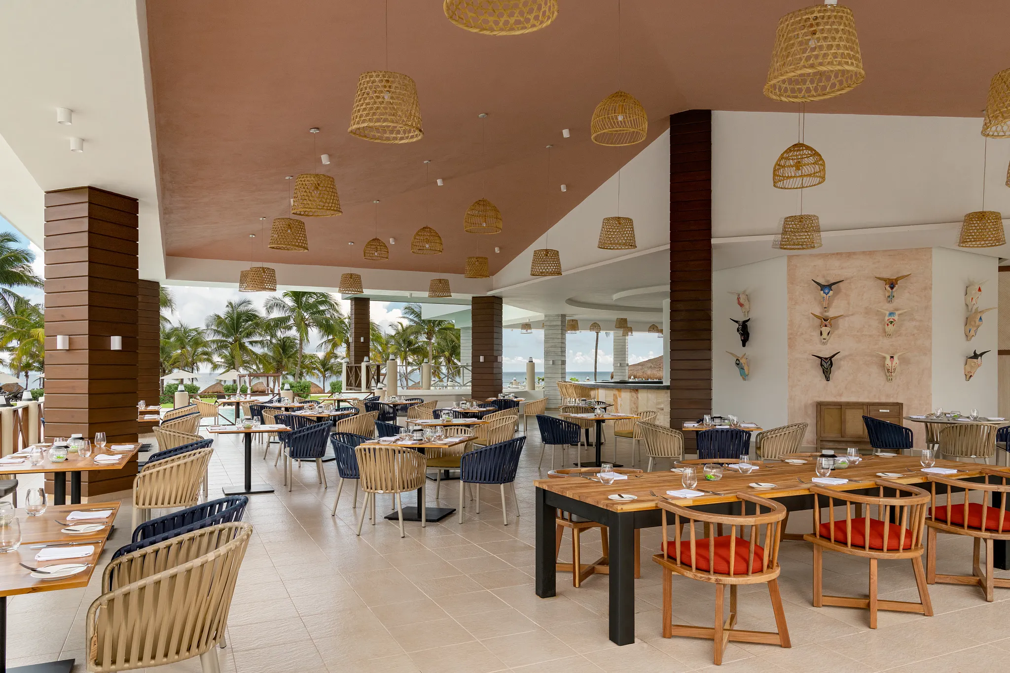 La Parrilla open-fire grill restaurant at Dreams Puerto Morelos Resort & Spa featuring open-air dining, wood accents, and tropical ocean views.