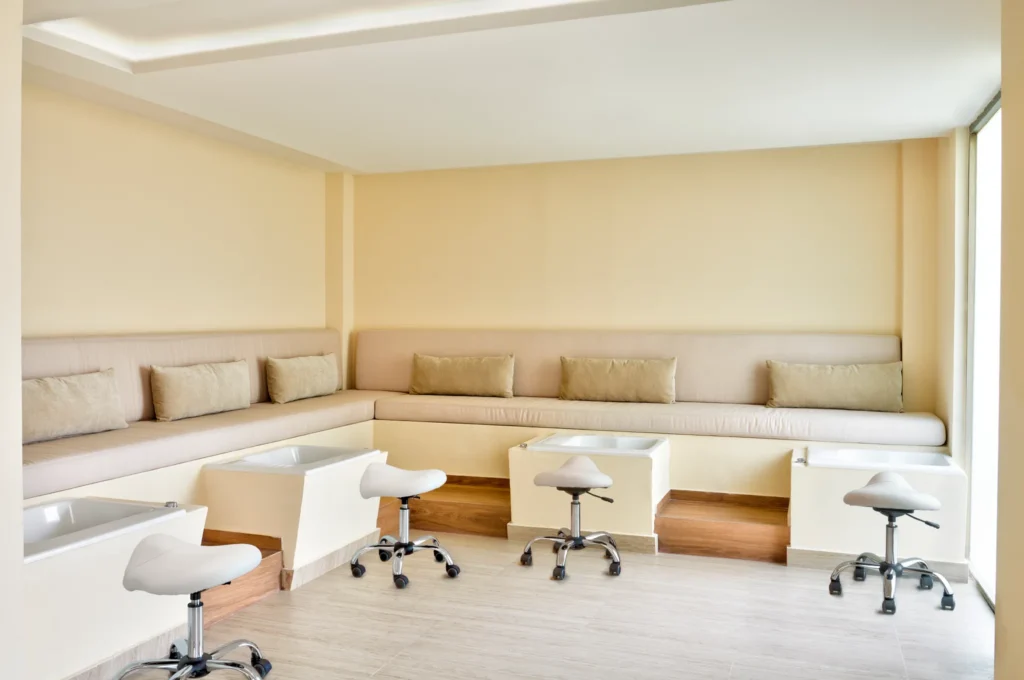 Indoor pedicure lounge with cushioned seating and foot spa basins at Dreams Puerto Morelos Resort & Spa.