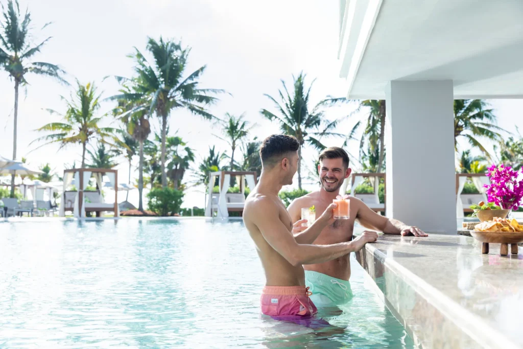 Two guests enjoying cocktails at a swim-up bar in the pool at Dreams Puerto Morelos Resort & Spa.
