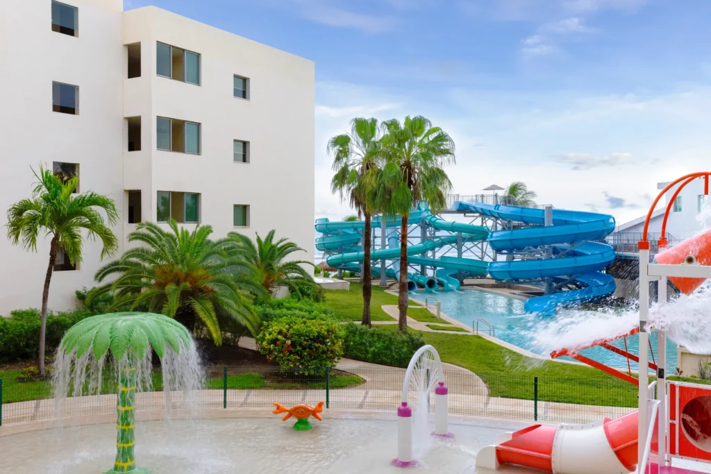 Large water slides and splash area near resort buildings at Dreams Puerto Morelos Resort & Spa.