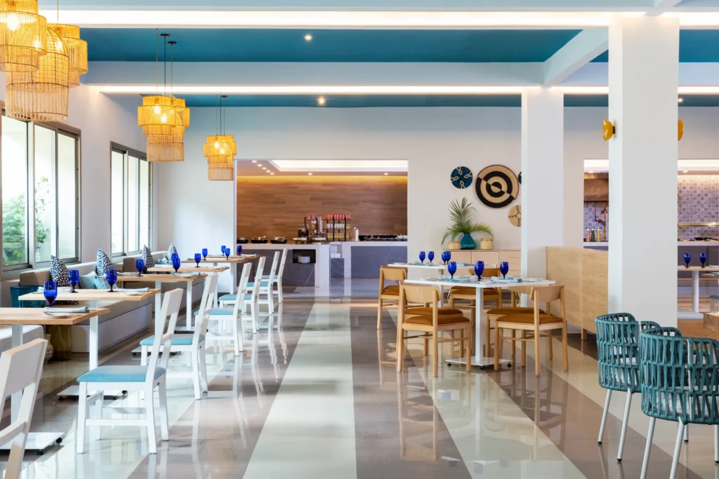 World Café buffet restaurant at Dreams Puerto Morelos Resort & Spa featuring modern dining space, blue glassware, and bright coastal-inspired décor.