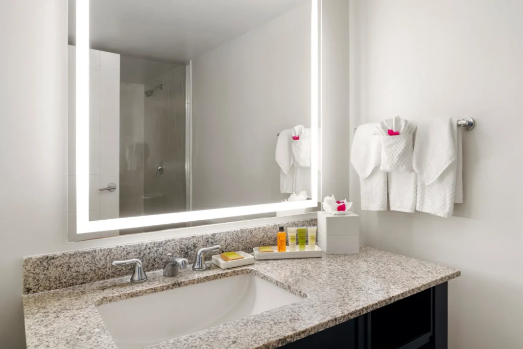 Oceanfront Royal Suite bathroom with granite vanity and illuminated mirror at Dreams Rose Hall Resort & Spa.