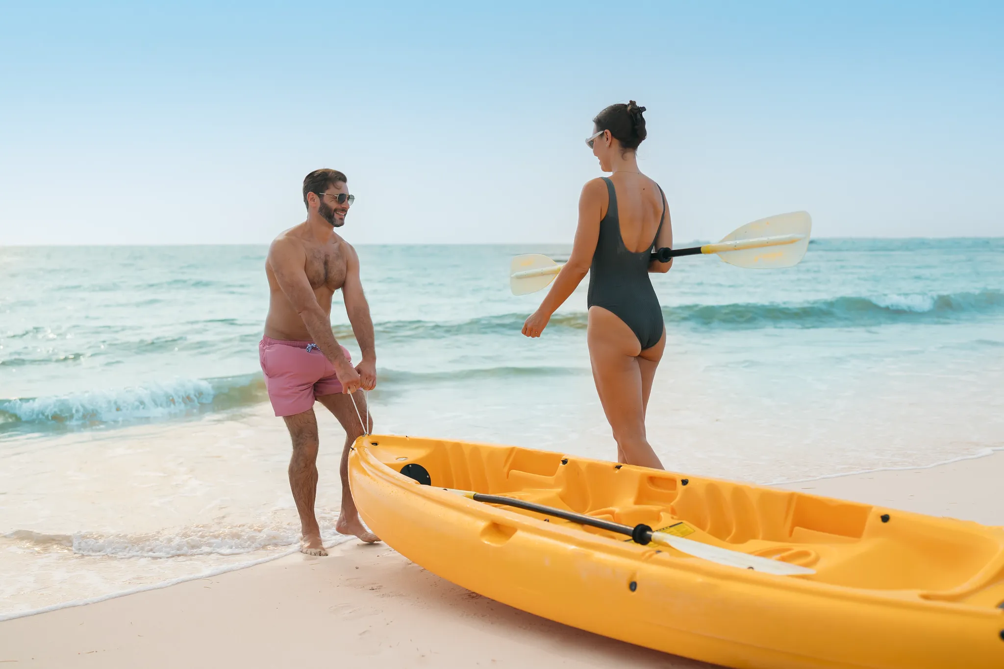 Couple preparing for a beach kayaking adventure at Dreams Royal Beach Punta Cana, enjoying fun ocean activities in a tropical setting.