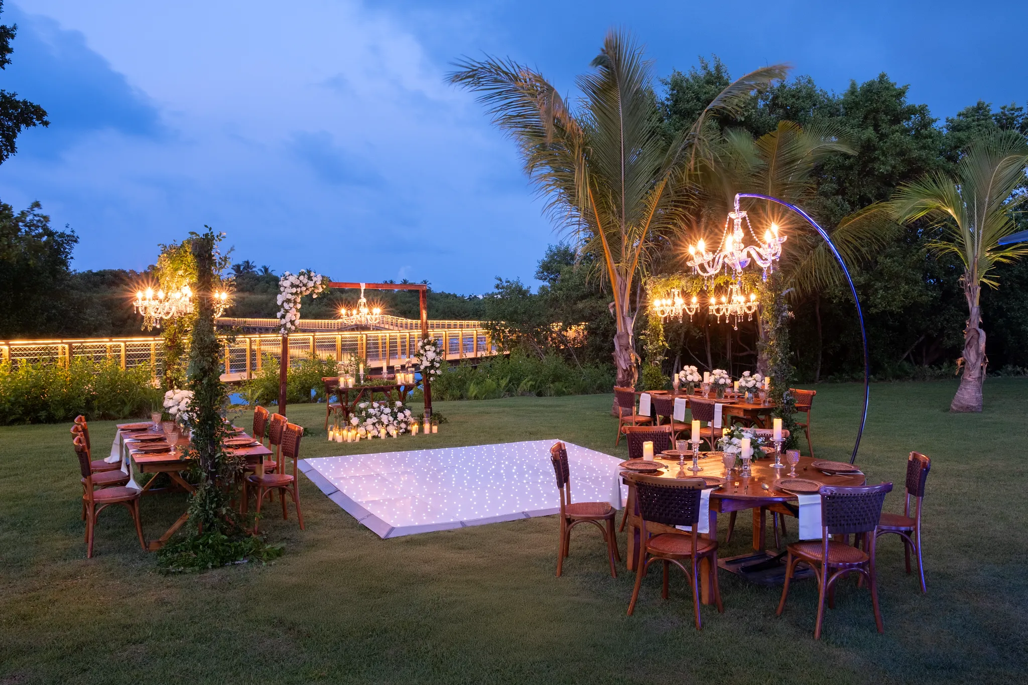 Garden wedding reception setup with chandeliers and dance floor at Dreams Royal Beach Punta Cana