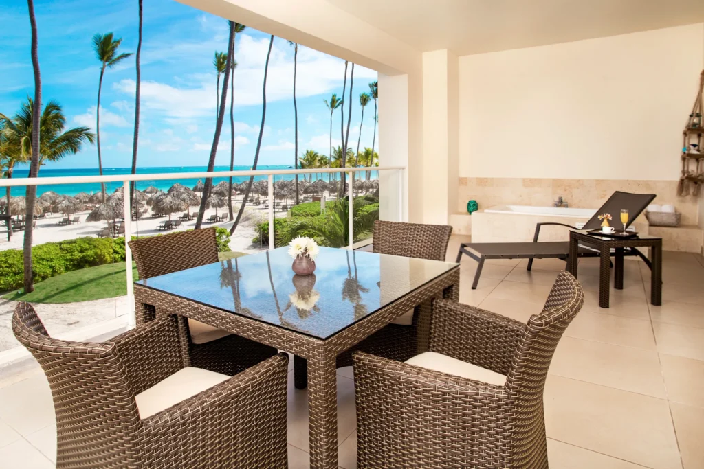 Private balcony with dining table, loungers, hot tub, and oceanfront view.