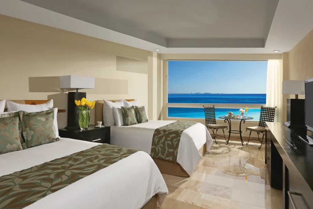 Deluxe Partial Ocean View room with two double beds and ocean views at Dreams Sands Cancun Resort & Spa.