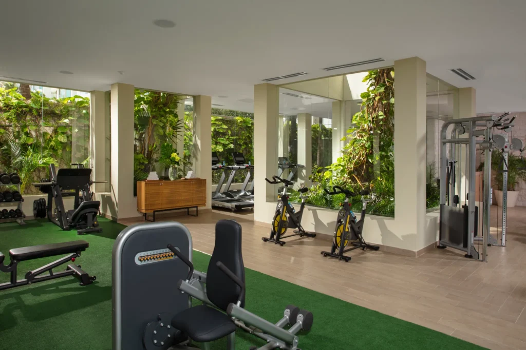 Modern fitness center with cardio equipment and tropical garden views at Dreams Sands Cancun Resort & Spa.