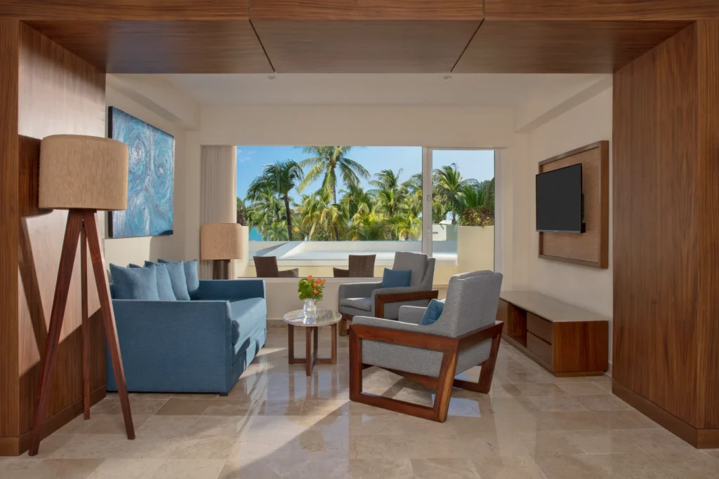 Preferred Club Premium Junior Suite Tropical View living area with sofa and tropical views at Dreams Sands Cancun Resort & Spa.