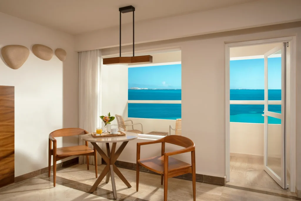 Preferred Club Premium Ocean Front with Balcony dining area overlooking the Caribbean Sea at Dreams Sands Cancun Resort & Spa.
