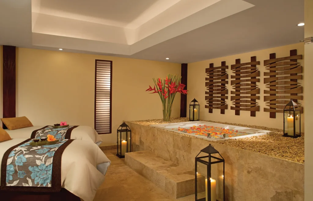 Couples spa suite with massage beds and flower-filled whirlpool tub at Dreams Sapphire Resort & Spa.
