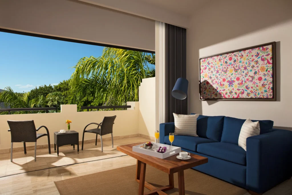 Deluxe Junior Suite Tropical View living area with sofa and private furnished terrace at Dreams Sapphire Resort & Spa.