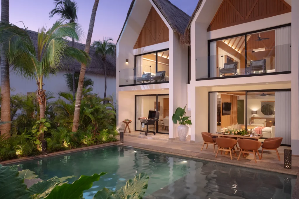 Luxury villa with private pool and outdoor dining area at Dreams Sapphire Resort & Spa illuminated at sunset.