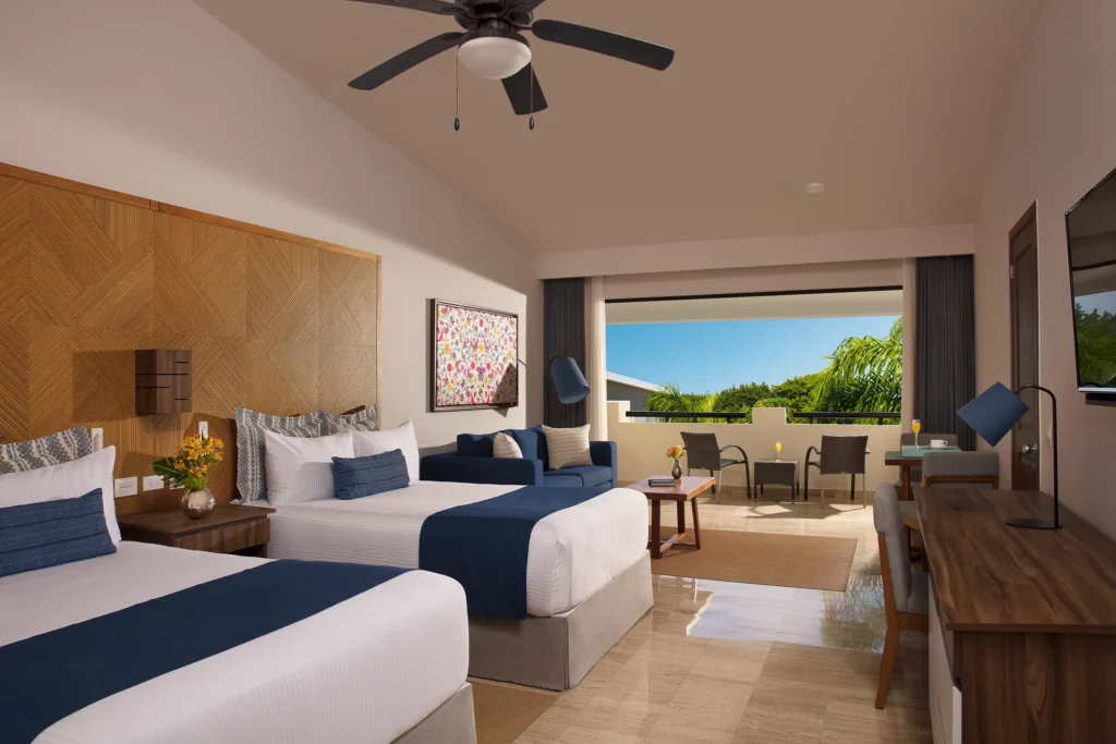 Preferred Club Junior Suite Tropical View with two double beds and furnished balcony at Dreams Sapphire Resort & Spa.