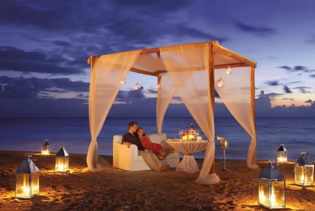 Couple enjoying a private candlelit beach dinner under a romantic cabana at Dreams Sapphire Resort & Spa in Riviera Maya.