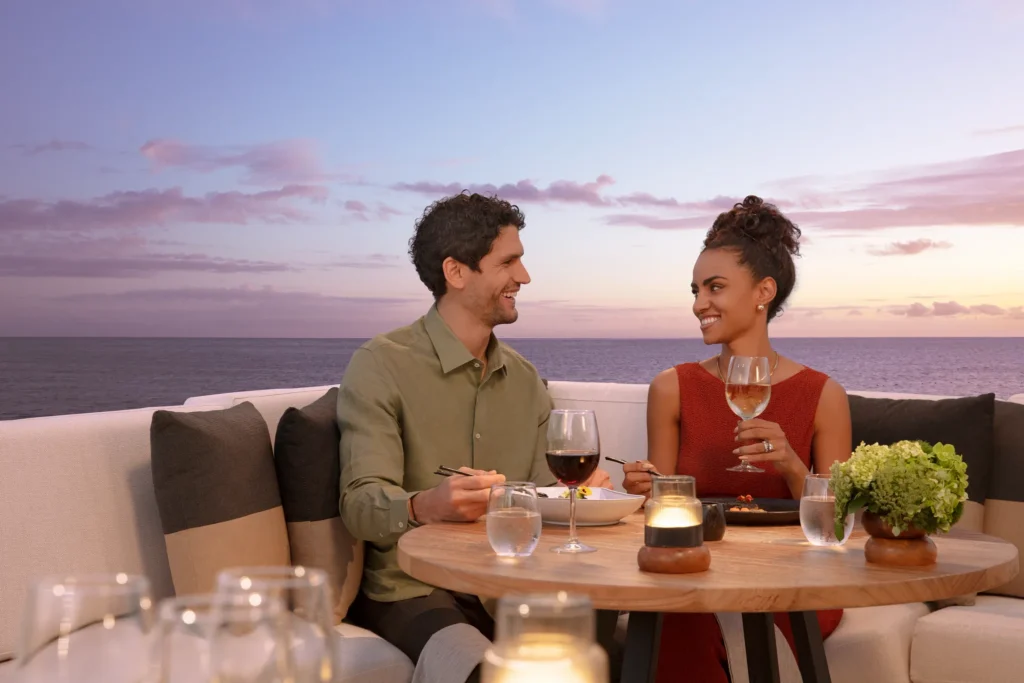 Couple enjoying a romantic dinner with ocean views at Dreams Sapphire Resort & Spa during sunset.