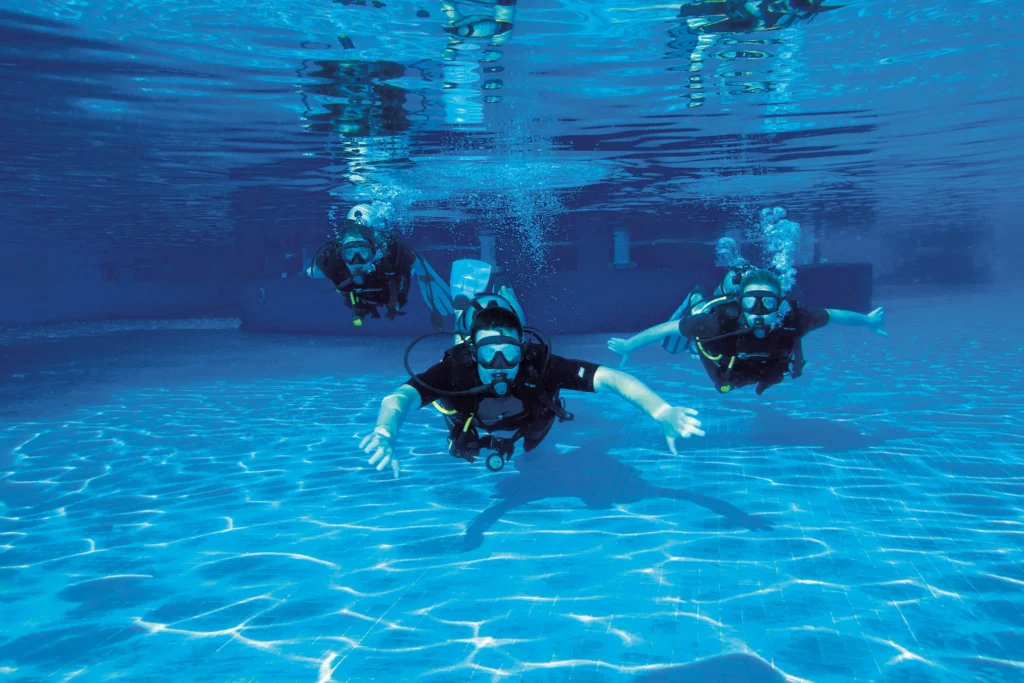 Guests participating in a scuba diving lesson in a resort pool at Dreams Sapphire Resort & Spa, perfect for family-friendly aquatic adventures.