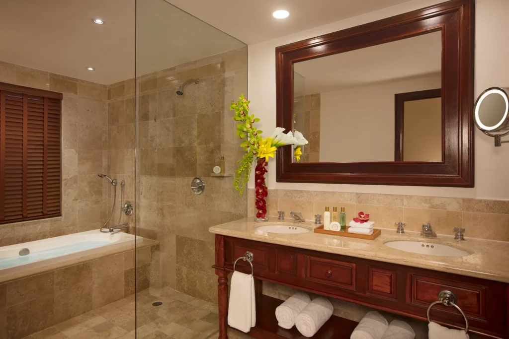 Marble bathroom with double vanity, walk-in shower, soaking tub, and large mirror in the Preferred Club Junior Suite Ocean Front at Dreams Tulum Resort & Spa.