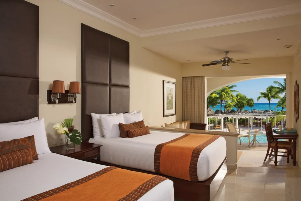 Preferred Club Junior Suite Ocean Front with two double beds and a furnished balcony overlooking the ocean at Dreams Tulum Resort & Spa.