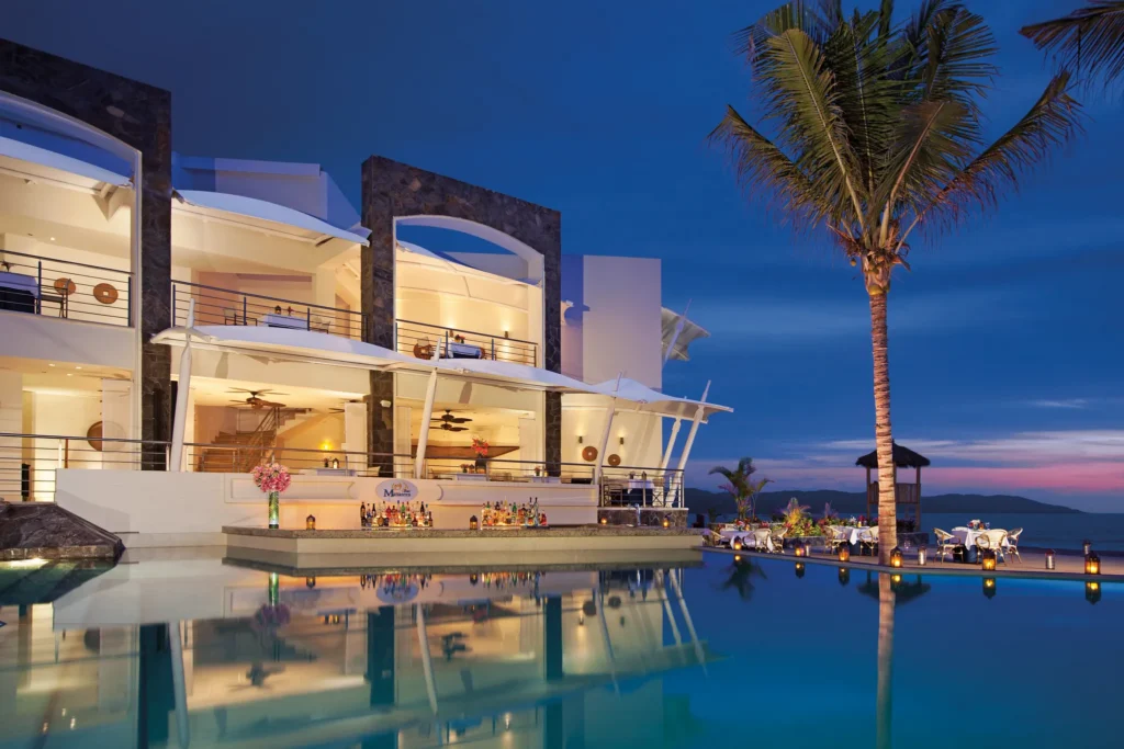 Castaways seafood restaurant at Dreams Vallarta Bay Resort & Spa overlooking the infinity pool and ocean at sunset with elegant outdoor dining.