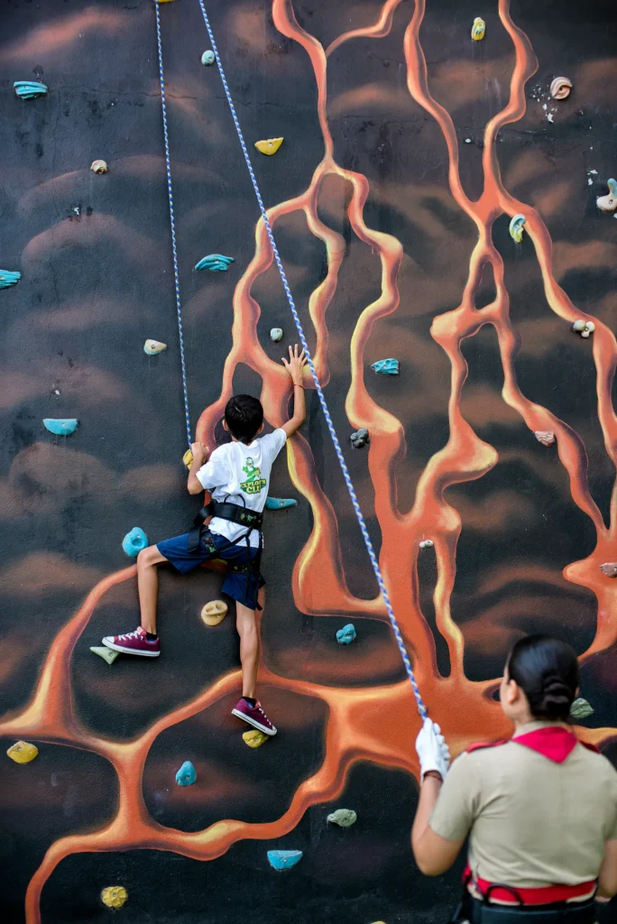 Child climbing an adventure wall at Dreams Vallarta Bay Resort & Spa with staff supervision.