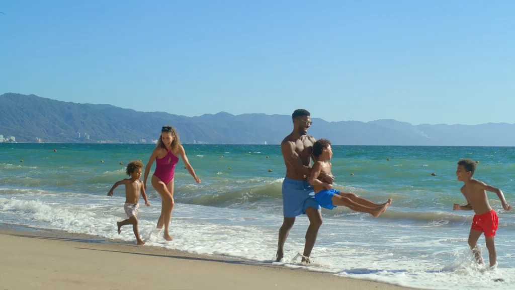 Family playing together along the beach at Dreams Vallarta Bay Resort & Spa in Puerto Vallarta.