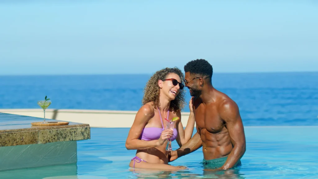 Couple enjoying cocktails together in an infinity pool overlooking the ocean at Dreams Vallarta Bay Resort & Spa.