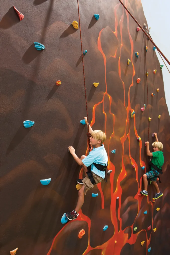 Kids climbing a colorful rock wall at Dreams Vallarta Bay Resort & Spa Explorer’s Club activity area.