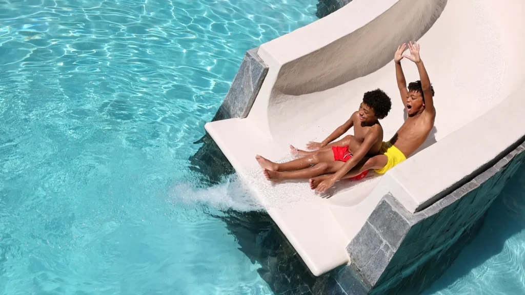 Children laughing while sliding into a pool at Dreams Vallarta Bay Resort & Spa family water park in Puerto Vallarta.