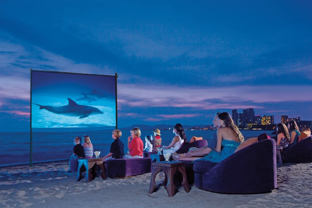 Families watching a movie on the beach at night at Dreams Vallarta Bay Resort & Spa in Puerto Vallarta.