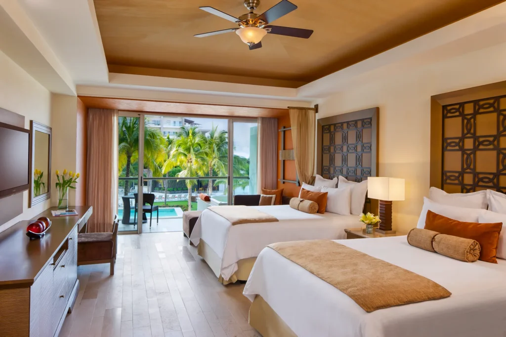 Preferred Club Junior Suite Garden View with two double beds and balcony at Dreams Vallarta Bay Resort & Spa.