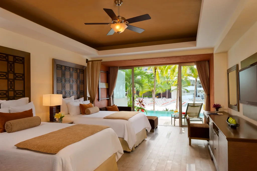 Preferred Club Junior Suite Swim Out with two double beds and terrace pool access at Dreams Vallarta Bay Resort & Spa.