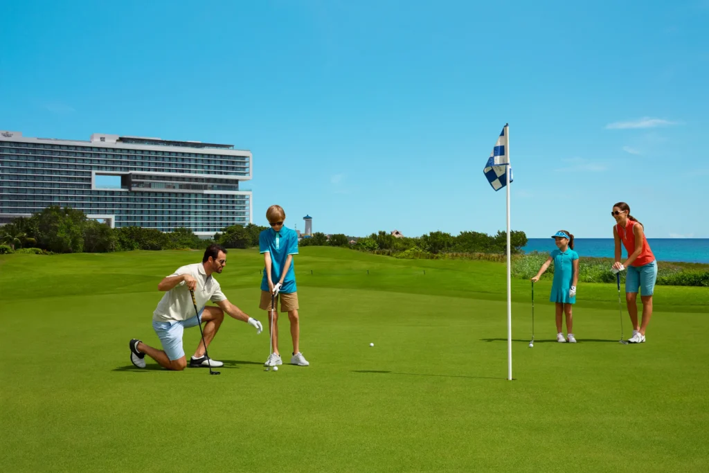 Family golfing together on a lush course near Dreams Vista Cancun Golf & Spa Resort with ocean views.