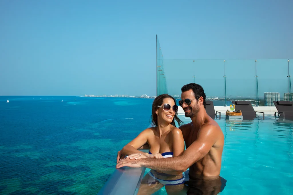 Couple relaxing in rooftop infinity pool overlooking the ocean at Dreams Vista Cancun Golf & Spa Resort.