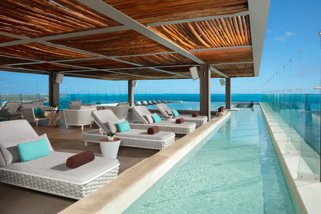 Rooftop pool lounge area with cabanas and ocean views at Dreams Vista Cancun Golf & Spa Resort.