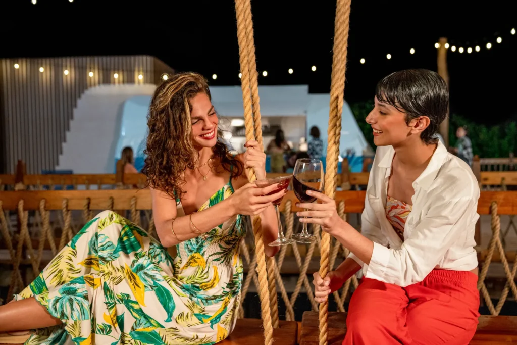 Guests toasting cocktails at a lively bar with open kitchen at Hyatt Vivid Grand Island in the evening.
