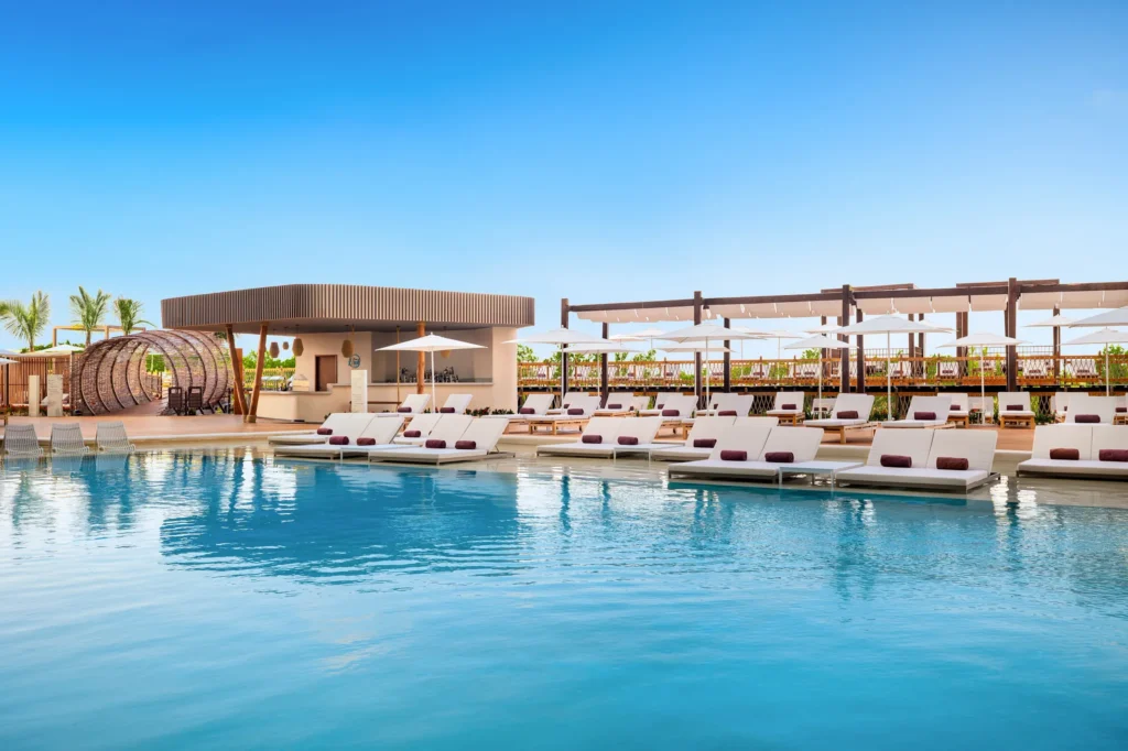 Main pool with in-water loungers and umbrellas at Hyatt Vivid Grand Island under a clear blue sky.