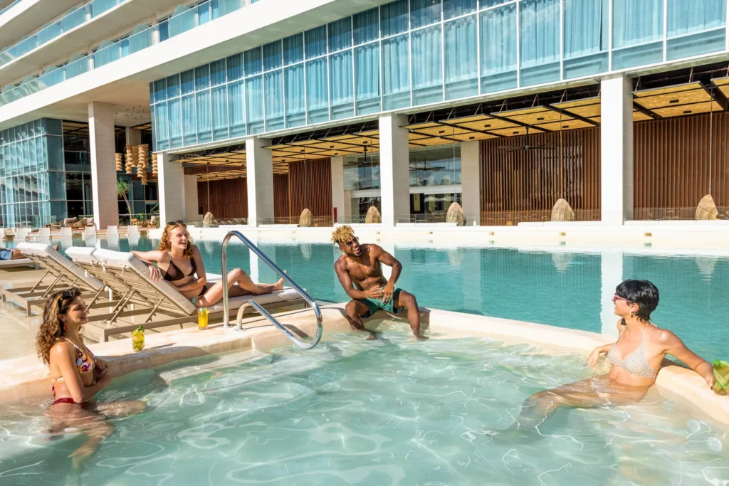 Guests relaxing in a shallow pool area with lounge chairs and cocktails at Hyatt Vivid Grand Island.