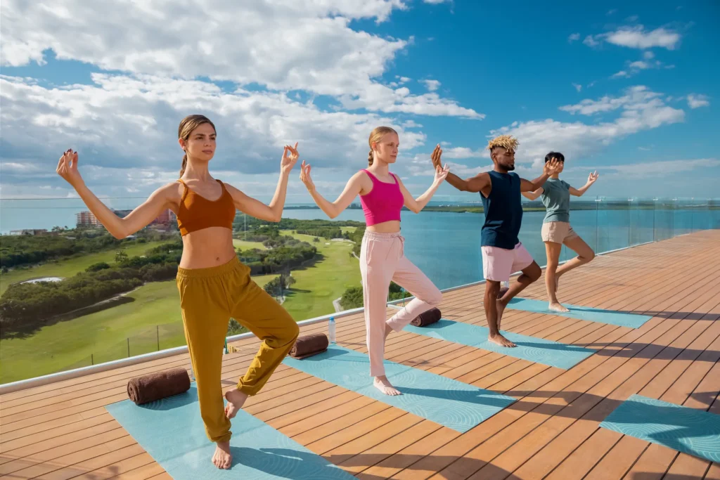 Guests practicing yoga on a rooftop deck overlooking the lagoon at Hyatt Vivid Grand Island in Cancun.
